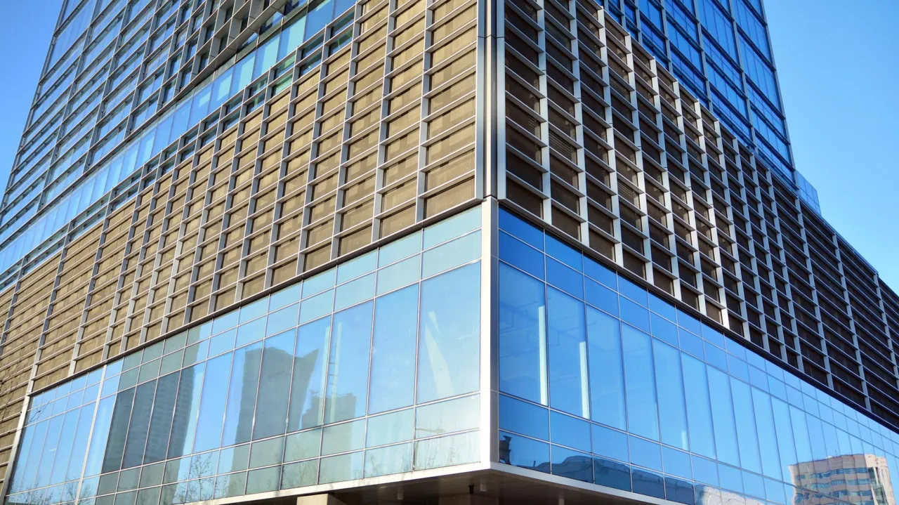 A row of Manx office buildings reflected in glass under a cool overcast sky