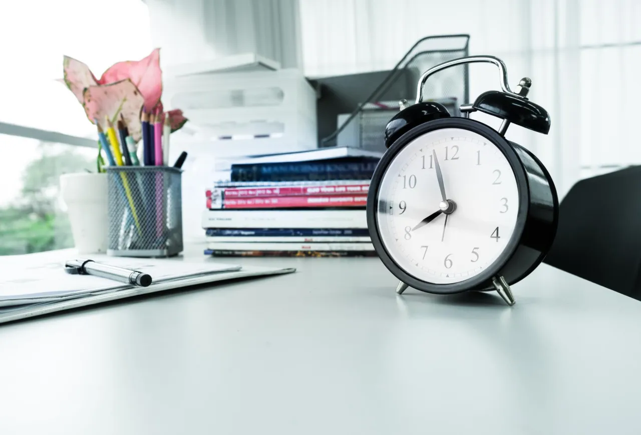 A clock and an open onboarding file on an office desk, signalling assessment before onboarding