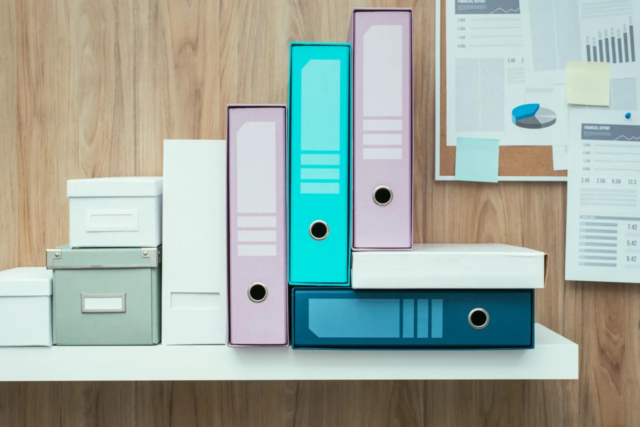 Three document folders feeding a single binder on a navy desk