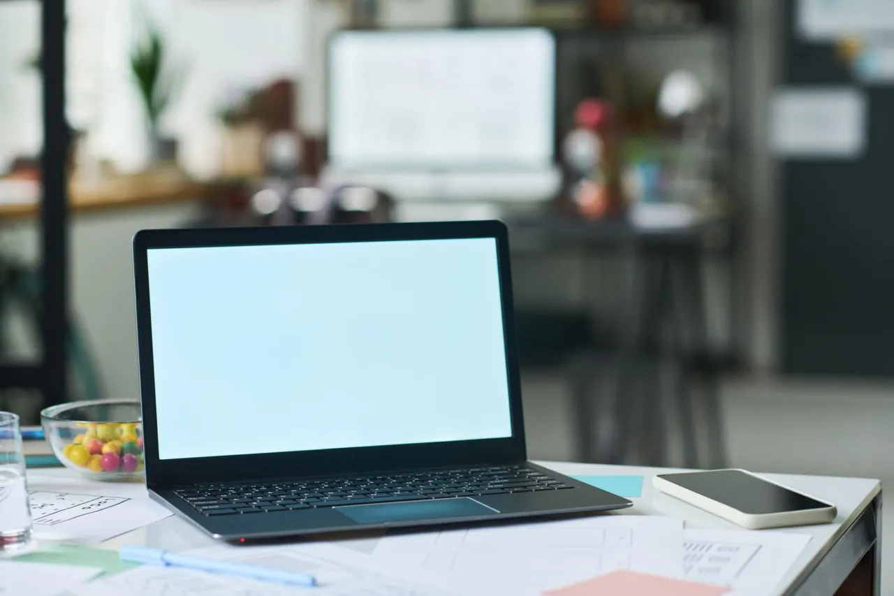A laptop showing an e-onboarding flow beside a printed compliance assessment