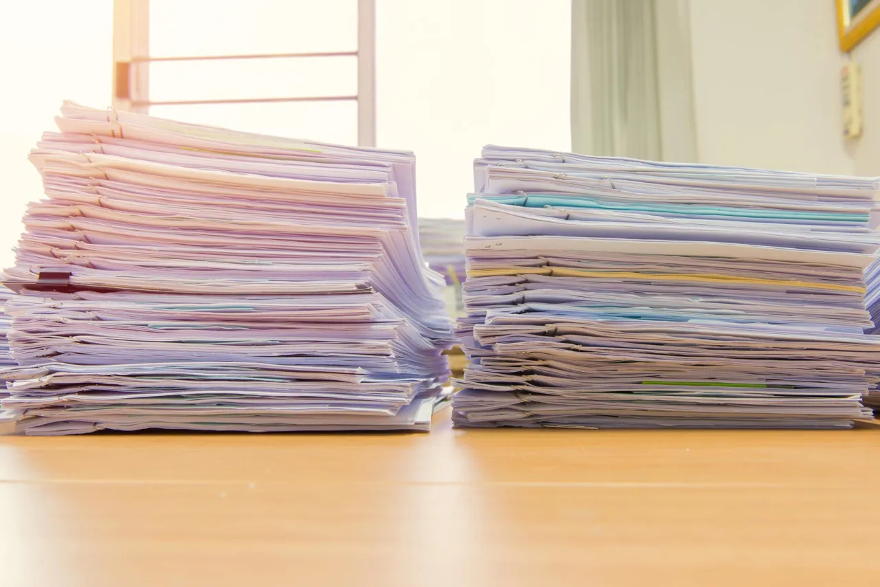 Two contrasting documents on a desk, one a generic template and one annotated with firm-specific notes