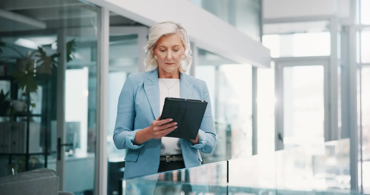 A senior manager reviewing a compliance file with a direct line of sight to the boardroom