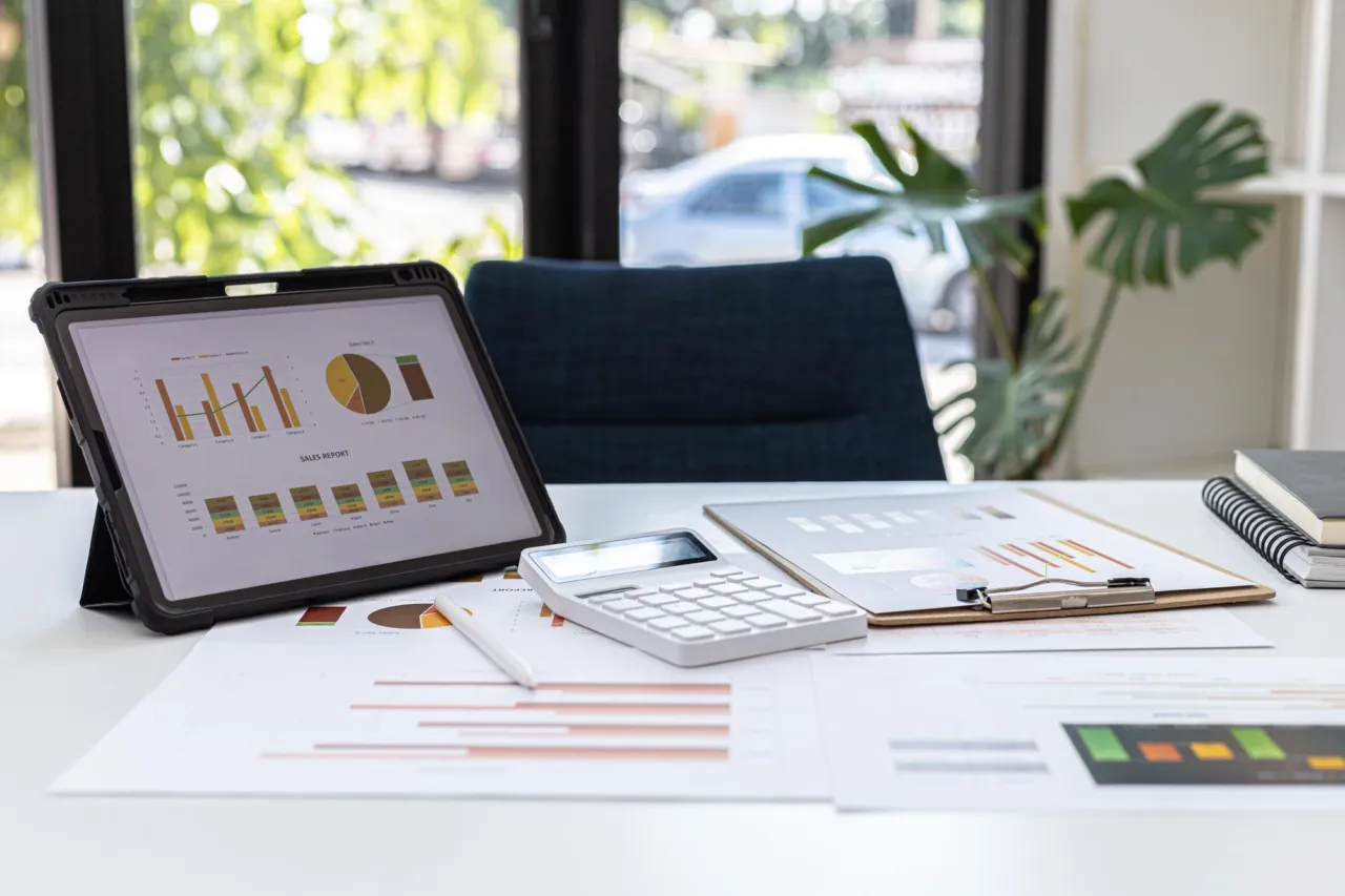 A reviewed compliance report on a desk with earlier findings visible beneath it