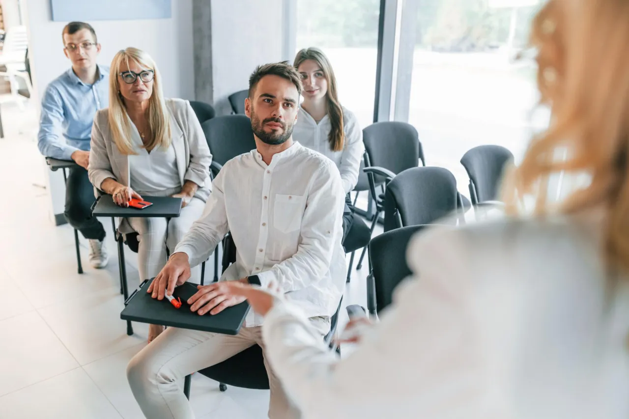 Compliance officer leading a small AML/CFT training session around a table in an Isle of Man office