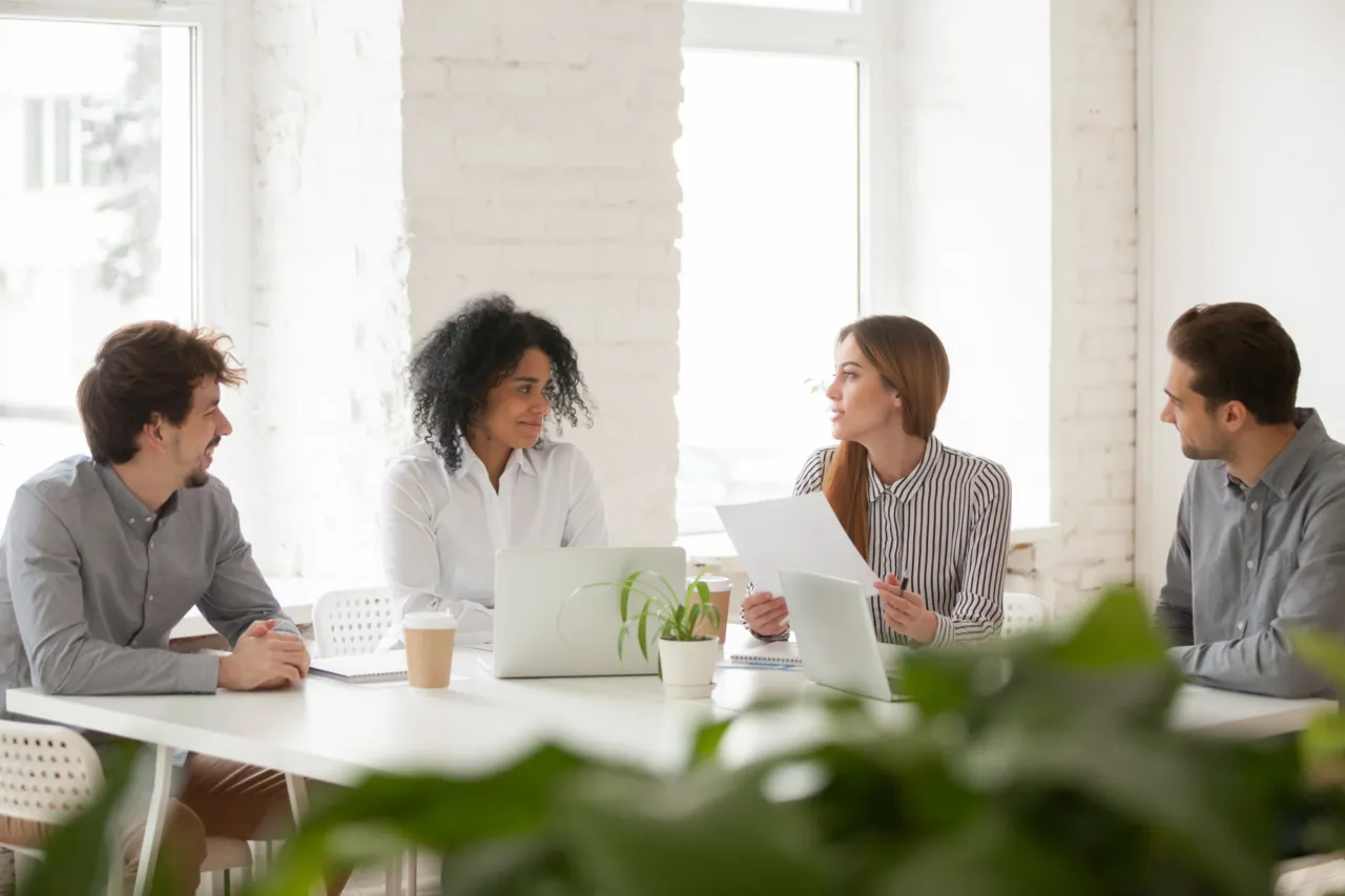 Small group of colleagues in discussion during a compliance training session in an Isle of Man office