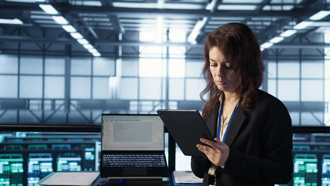 An IT professional checking a tablet in a data centre aisle