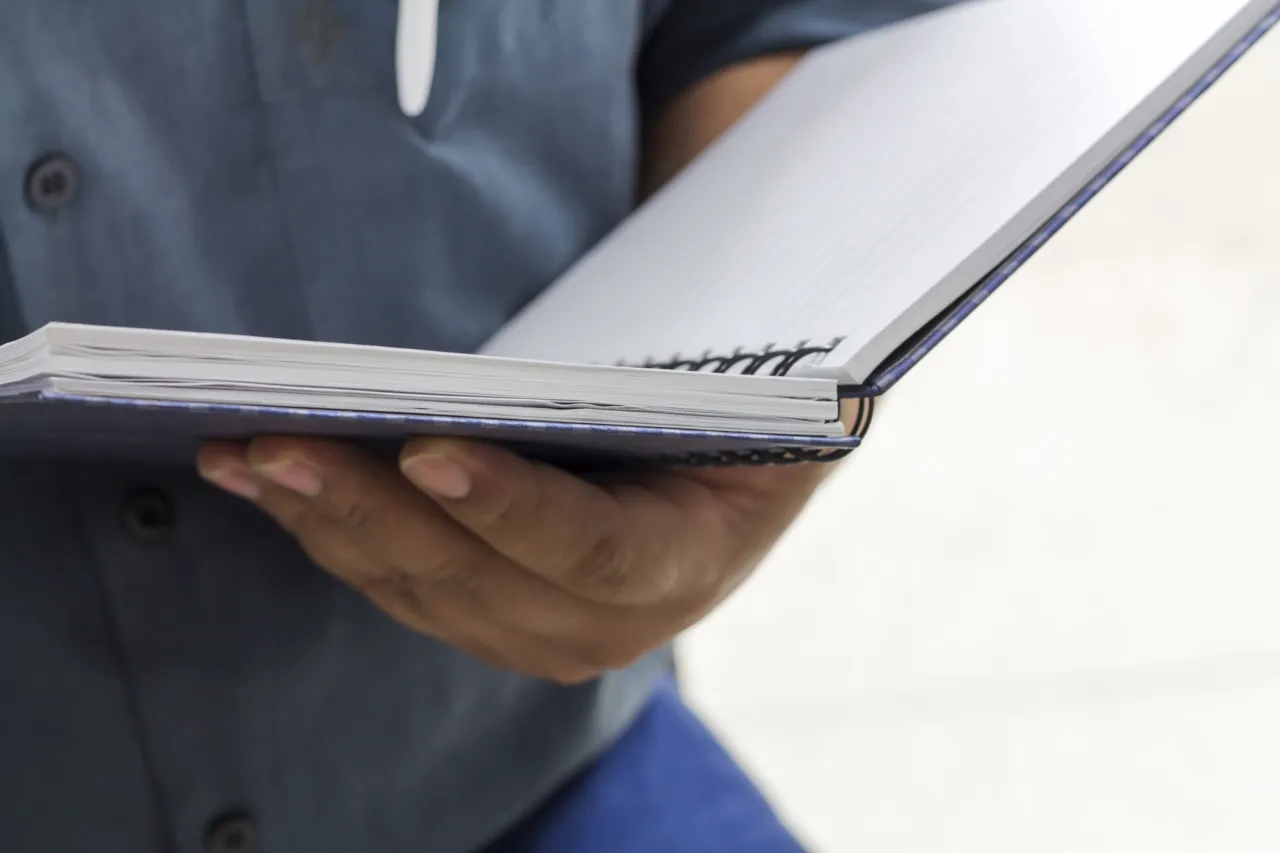 A man reading through an open ring binder of procedures