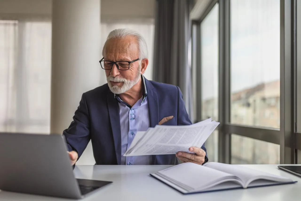 A senior compliance officer at a desk reviewing an internal disclosure in a calm Isle of Man office