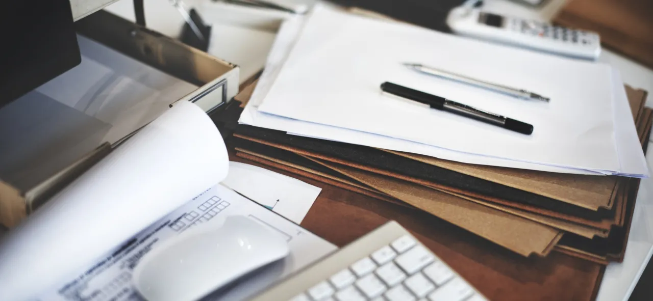 A workplace desk with documents, a pen and a keyboard
