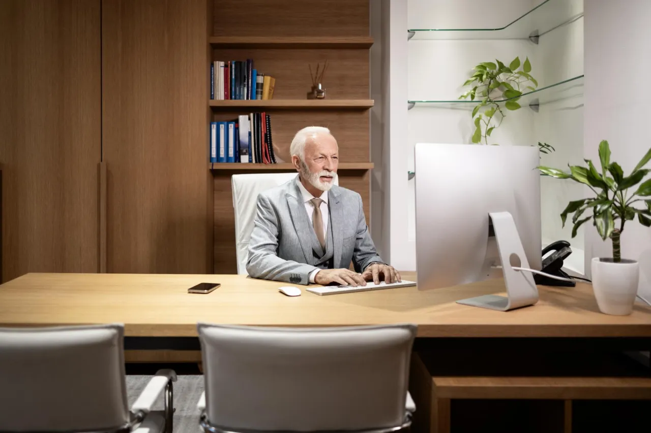 A senior executive working at a desk in a wood-panelled office