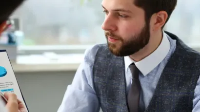 A compliance officer reviewing a business risk assessment document in a calm Isle of Man office