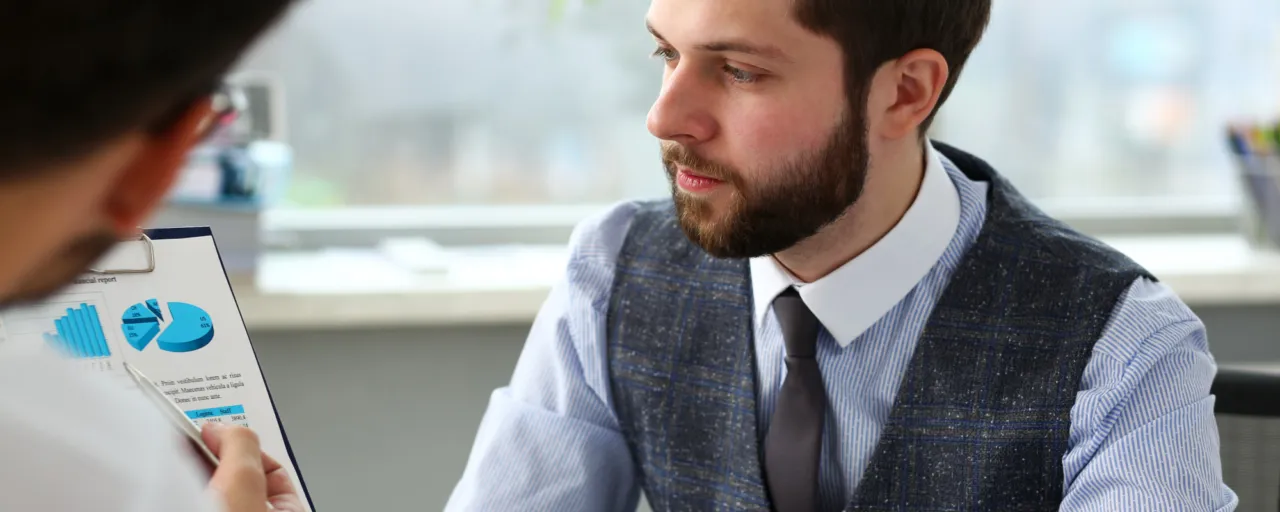 A compliance officer reviewing a business risk assessment document in a calm Isle of Man office