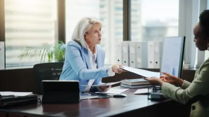 A compliance officer reviewing customer files at a desk in a calm Isle of Man office