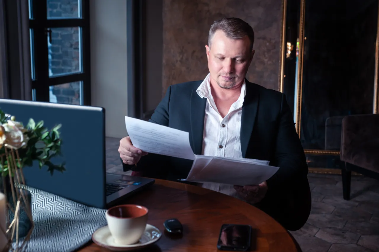 A senior executive in a dark suit reading through papers at a desk